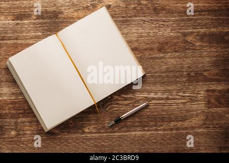 Ouvrez le carnet avec des pages blanches jaunes et un stylo plume sur un fond en bois. Banque D'Images