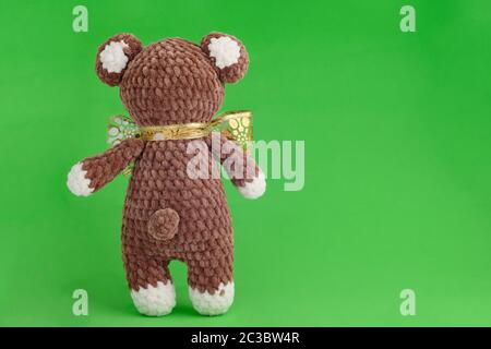 Ours en peluche tricoté pour enfants avec noeud sur fond vert Banque D'Images