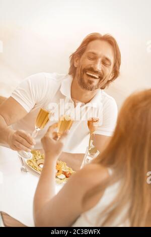 Couple aimant élevant des lunettes de champagne ayant un événement au café de la plage. Attention sélective sur rire l'homme contre le fond de la mer. Angle néerlandais Banque D'Images