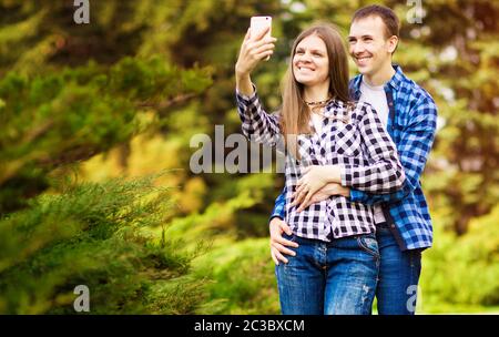 La Capture de moments lumineux. Jeune couple aimant faire joyeuse sur selfies caméra lors de standing outdoors Banque D'Images