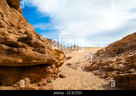 Homme en vêtements arabes blancs marche dans un canyon coloré en Egypte Dahab Sud Sinaï Banque D'Images