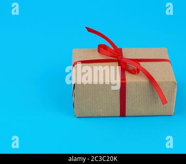 Fort est emballé dans du papier kraft brun et attachées avec un ruban de soie fine rouge sur fond bleu Banque D'Images