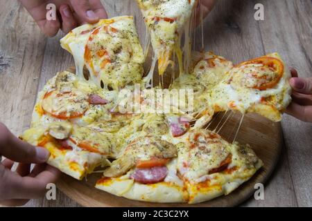 Les gens sont à l'arraché des morceaux de pizza à la mozzarella et les tomates. salami. Top vues Banque D'Images