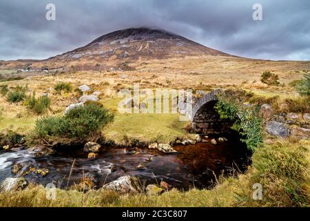Vieux petit pont en pierre sur la rivière avec vue sur la montagne Errigal Banque D'Images