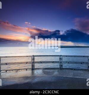 Un lever de soleil hiverne sur la jetée de Tynemouth, qui donne sur les rampes de l'autre côté du port sur la mer du nord et la lumière du soleil levant sur les nuages Banque D'Images