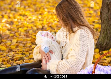 Maman poussa dans le parc, marchant avec un bébé nouveau-né Banque D'Images