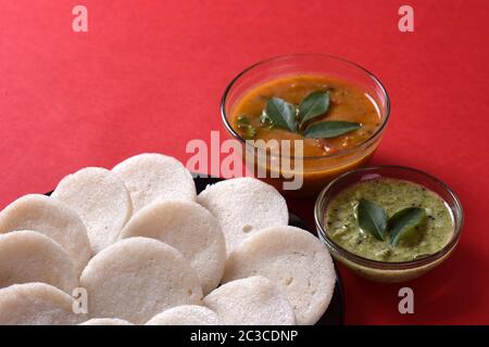 Idli avec noix de coco Chutney et Sambar sur fond rouge plat indien, l'Inde du Sud : des aliments préférés rava idli ou semoule ou bras croisés les bras croisés, servi avec rava Banque D'Images