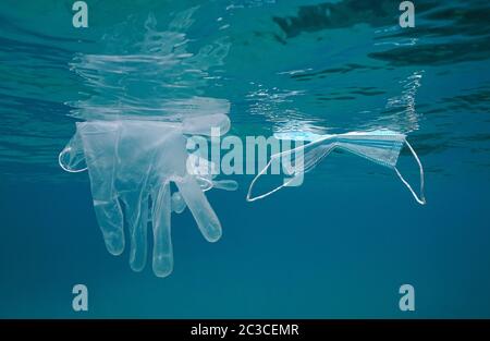 Masque et gants flottent sous la surface de l'eau dans la mer, pollution des déchets plastiques depuis la pandémie du coronavirus COVID-19 Banque D'Images