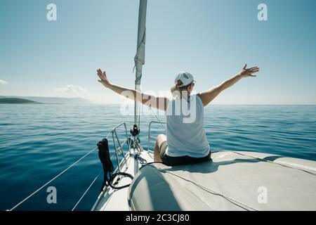 Femme assise sur les bateaux Bow appréciant le voyage en yacht avec les bras larges ouverts. Voile, navigation de plaisance et tr Banque D'Images