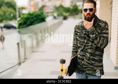 Jeune homme marchant avec la longboard dans la rue Banque D'Images