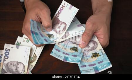 Un homme du Caucase considère un nouvel argent papier ukrainien. Mains de sexe masculin tenant un paquet de billets valeur nominale 1000 hryvnia. Gros plan Banque D'Images