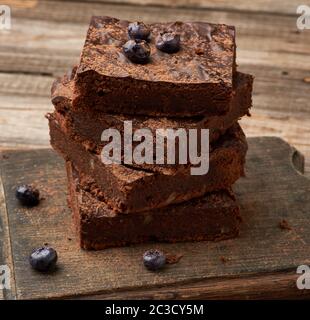 Pile de tranches au four carrés du brownie au chocolat avec noix sur une surface en bois. La cuisson des plats faits maison. Pâtisserie au chocolat. Des repas faits maison, sucré Banque D'Images