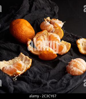 tas de mandarine orange mûre ronde non pelée sur une serviette noire, table en bois, clé basse Banque D'Images