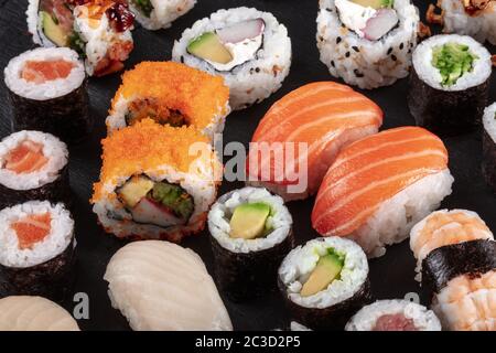 Grand sushi sur noir. Un assortiment de maki, nigiri et rouleaux Banque D'Images