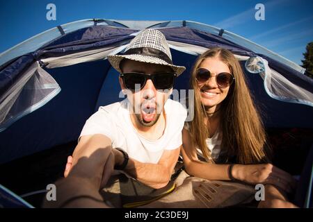 Camping drôle de couple en tente prenant selfie. Des amis heureux qui s'amusent à togheter. Concept de mode de vie actif et de technologie Banque D'Images