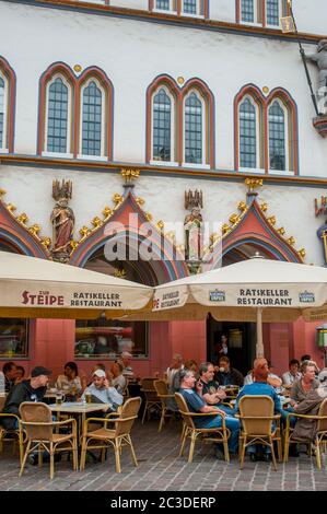 Les gens assis dans un café-terrasse sur la place du marché à Trèves, en Allemagne. Banque D'Images