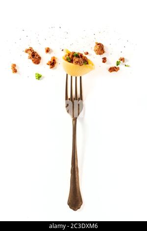Pâtes italiennes. Une fourchette d'époque avec un conchiglie, de la viande hachée et du persil, arrosé de poivre noir, tiré du haut sur un W. Banque D'Images
