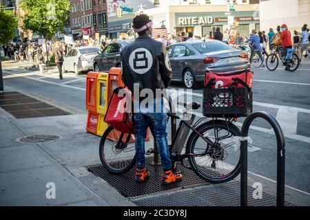 Un employé de GrubHub à Chelsea à New Yorkwatches une manifestation de Black Lives Matter qui passe le mardi 16 juin 2020. (© Richard B. Levine) Banque D'Images