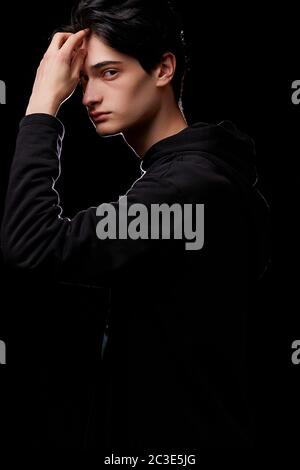 portrait dramatique d'un jeune homme en noir sur fond noir Banque D'Images