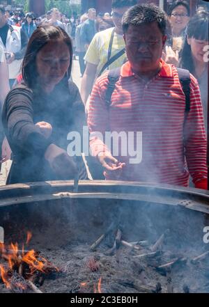 Tourisme tirant de la fumée (croyez avoir des propriétés de guérison) de Jokoro ou brûleur d'encens à eux-mêmes au Temple Sensoji à Tokyo, Japon. Banque D'Images