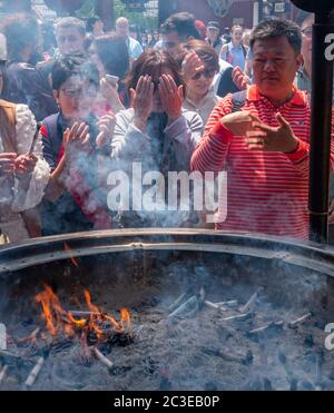 Tourisme tirant de la fumée (croyez avoir des propriétés de guérison) de Jokoro ou brûleur d'encens à eux-mêmes au Temple Sensoji à Tokyo, Japon. Banque D'Images