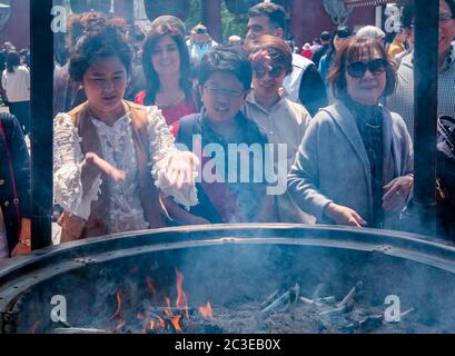 Tourisme tirant de la fumée (croyez avoir des propriétés de guérison) de Jokoro ou brûleur d'encens à eux-mêmes au Temple Sensoji à Tokyo, Japon. Banque D'Images