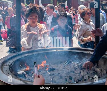 Tourisme tirant de la fumée (croyez avoir des propriétés de guérison) de Jokoro ou brûleur d'encens à eux-mêmes au Temple Sensoji à Tokyo, Japon. Banque D'Images