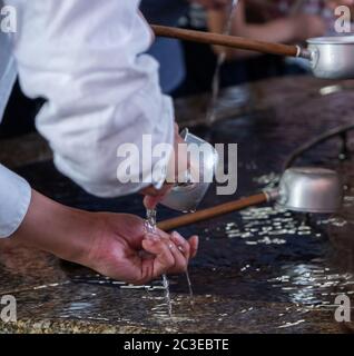 Les touristes se purifient d'eau avant d'entrer dans le temple Sensoji, Tokyo, Japon Banque D'Images