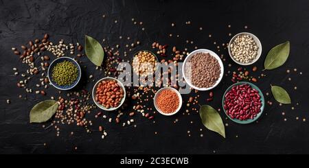 Légumineuses panorama, tiré du dessus sur un fond noir. Lentilles, soja, pois chiches, haricots rouges, une vatiété des légumineuses Banque D'Images