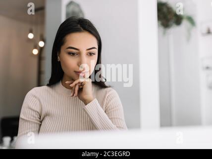 Gros plan portrait d'une femme indienne pensive utilisant un ordinateur portable, regardant des cours de formation en ligne. Indépendant asiatique travaillant à domicile Banque D'Images