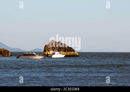 Krabi, Thaïlande - 14 février 2019 : un rocher doré près de la plage de grottes de Phra Nang. Dessinez un bandage. A proximité, il y a deux bateaux à grande vitesse avec des personnes qui inspectent les peintures. Banque D'Images