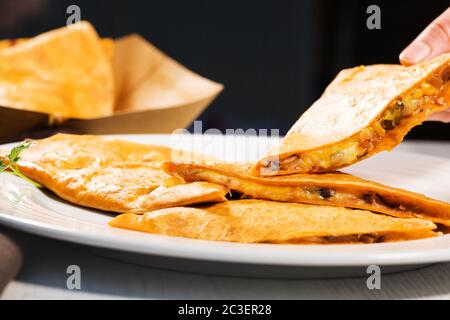 Quesadilla mexicaine avec poulet, haricots noirs, fromage et légumes sur plaque blanche. Banque D'Images