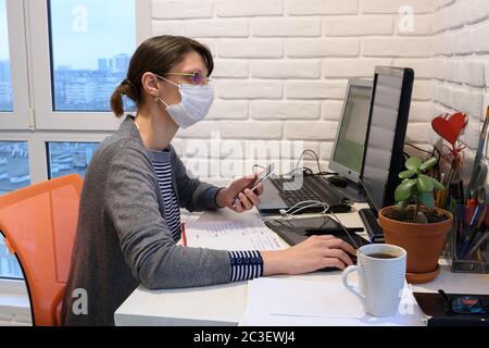 Une fille malade dans un masque médical en auto-isolation fonctionne à distance Banque D'Images