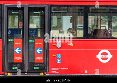 Une femme portant un masque médical sur un bus rouge londonien. Personne avec couverture de visage dans les transports publics. Maintenant une réglementation sur les transports publics Banque D'Images