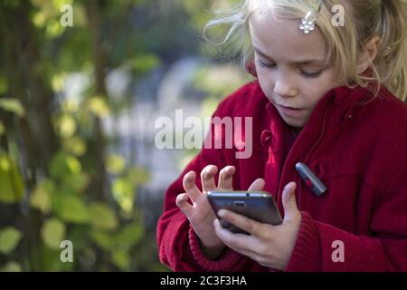 Fille (7) utilisant un smartphone, Kiel, Schleswig-Holstein, Allemagne Banque D'Images