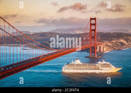 Vue panoramique du bateau de croisière passant par le célèbre Golden Gate Bridge avec la ligne d'horizon de San Francisco en arrière-plan au coucher du soleil, Californie, États-Unis Banque D'Images