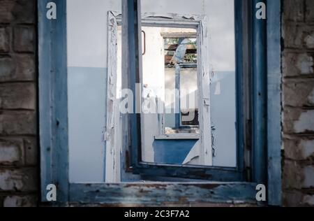 Vue de la fenêtre sur les murs, fenêtres, portes d'une maison abandonnée Banque D'Images