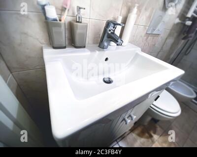 lavabo blanc avec robinet en acier chromé dans une petite salle de bains d'un appartement. Banque D'Images