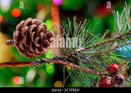 Branche d'arbre de Noël avec des cônes de pin et des baies rouges sur les lumières de noël. Banque D'Images