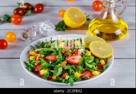 Salade saine d'arugula avec fraises, ananas et pistaches, graines de sésame, huile, citron et tomate cerise. Banque D'Images