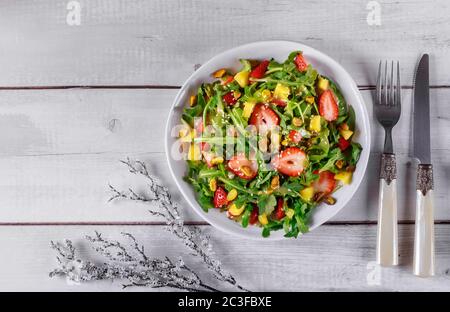 Salade saine d'arugula avec fraises, ananas et pistaches, graines de sésame, huile, citron et tomate cerise. Contenu de Noël. Banque D'Images