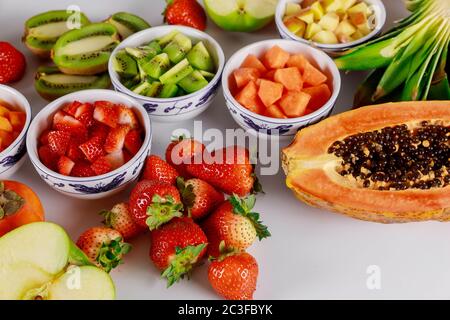 Faire une salade de fruits colorée à base de pomme, de papaye, de fraise, de kiwi et d'ananas. Banque D'Images