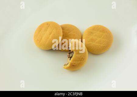 Biscuits cuits au four avec garniture au chocolat et un avec morsure manquante sur fond blanc Banque D'Images