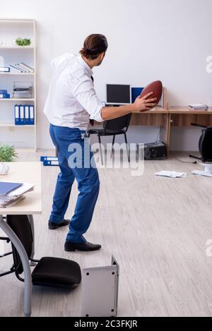 Un jeune homme lance un ballon de rugby dans le bureau Banque D'Images