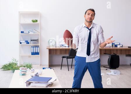 Un jeune homme lance un ballon de rugby dans le bureau Banque D'Images