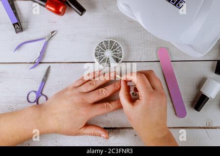 Femme met des rhinestones sur un ongle en gel rose. Faire de la manucure sur gel. Banque D'Images