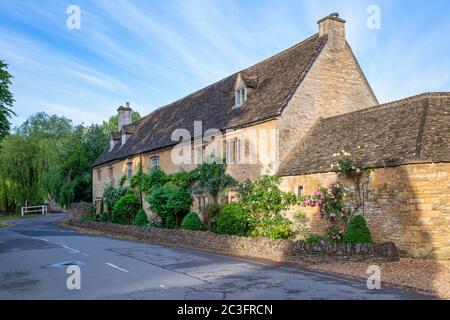 Maisons en pierre de Cotswold au début de la matinée en juin lumière du soleil. Lower Slaughter, Cotswolds, Gloucestershire, Angleterre Banque D'Images