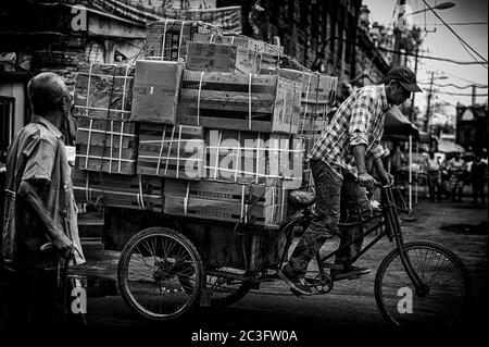 Photo en noir et blanc d'un pousse-pousse chinois transportant beaucoup de cargaison dans une rue de Harbin Banque D'Images