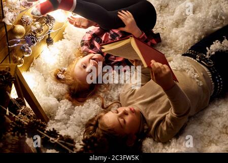 Les enfants lisent un livre dans une salle décorée pour Noël. Banque D'Images