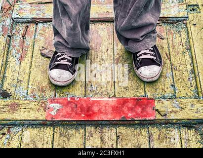 pieds d'un homme dans de vieilles chaussures sales sur un plancher en bois jaune Banque D'Images